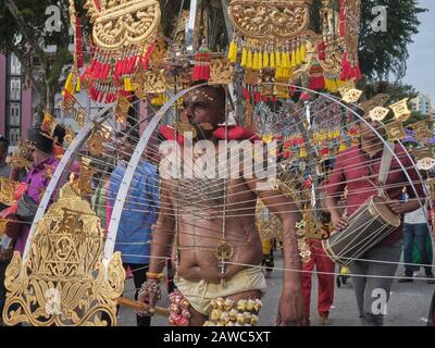 For Thaipusam Hindu festival, a participant is carrying a Kavadi in honor of god Murugan, accompanied by family and friends; Little India, Singapore Stock Photo