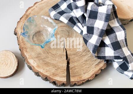Wooden rounds decoration for serving food. Oak cutting board with a crack, glass bowl and checked black and white kitchen towel Stock Photo
