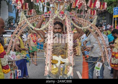 For Thaipusam Hindu festival, a participant is carrying an elaborate  Kavadi, including a sacred OM (ॐ) symbol, in honor of god Murugan; Singapore Stock Photo