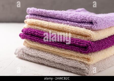 Terry towels for beauty and health. A stack of multi-colored towels lies on a white background. Lifestyle, housework. Copy space. Stock Photo