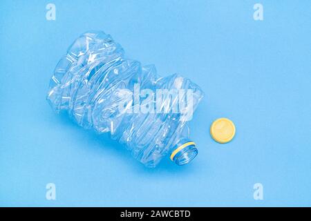 Crushed plastic bottle isolated on blue background. Recycling concept. Copy space Stock Photo