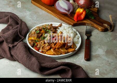 Peruvian dish Lomo saltado, made of beef tenderloin with red onion, yellow chili, tomatoes, with potato fries and rice. copy space Stock Photo