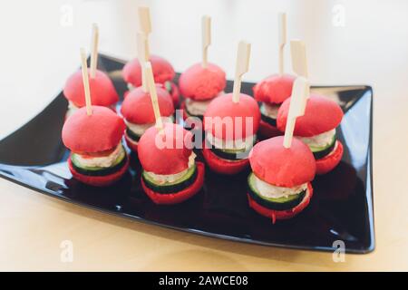Different canapes with smoked salmon, cucumber cherry tomatoes and mozzarella served on a table Stock Photo
