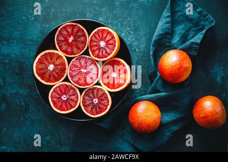 Cutted blood oranges in a plate on a dark blue background. Stock Photo