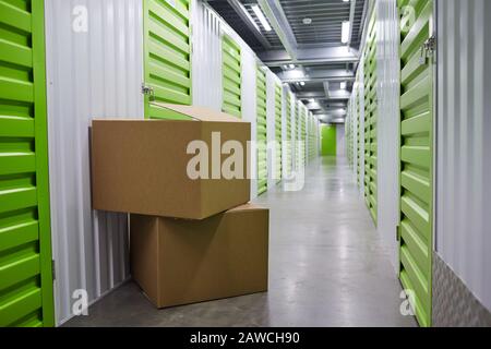 Image of stack of two big packages near the green storage boxes in storage room Stock Photo