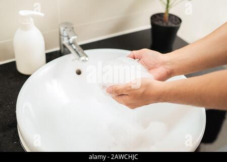 Hygiene concept. Man washes his hands in the bathroom with soap under running water. Stock Photo