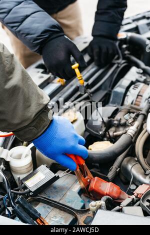 Two Car mechanic engineers checking, fixing the car, making maintenance comprehensive auto check. Auto mechanic charging car battery with electricity Stock Photo