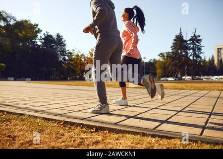 Back view sporty couple are running along the city street in the morning. Stock Photo