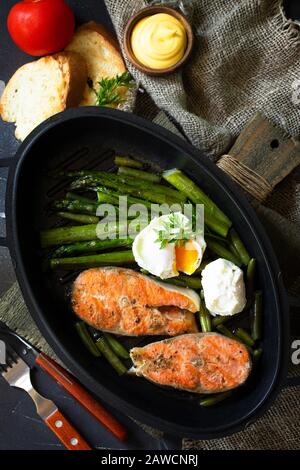 Green asparagus, grilled salmon and poached eggs. Healthy food on rustic wooden background. Top view flat lay background. Stock Photo