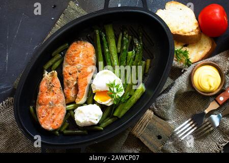 Green asparagus, grilled salmon and poached eggs. Healthy food on rustic wooden background. Top view flat lay background. Copy space. Stock Photo