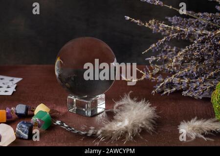 Divination with lavender, stones, feathers, fortune-telling ball. and cards Halloween background, occult and esoteric objects on witch wooden table, Stock Photo