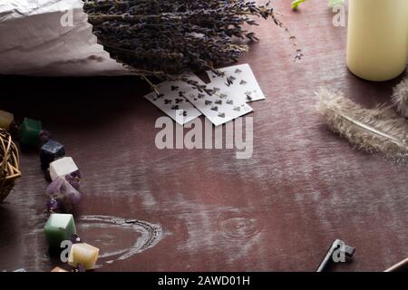 Divination with white candles, lavender, stones, feathers and cards. Halloween background, occult and esoteric objects on witch wooden table, copy spa Stock Photo