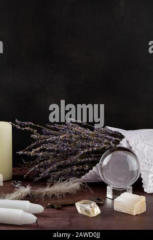 Divination with white candles, lavender, fortune-telling ball, stones. Halloween background, occult and esoteric objects on witch wooden table Stock Photo