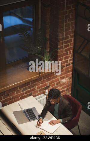 Young African businessman working at his workplace with laptop computer on it till late at office Stock Photo