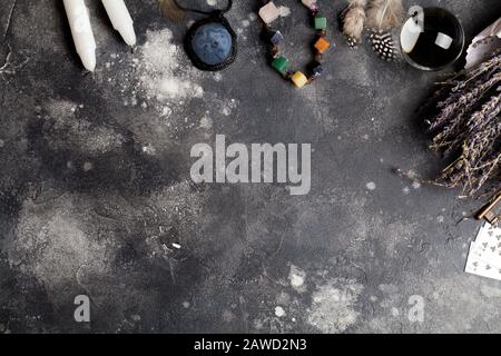 Divination with lavender, stones, feathers, fortune-telling ball, amulet and card. Halloween background, occult and esoteric objects on black backgrou Stock Photo