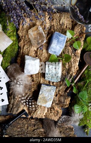 Divination with lavender, stones, feathers, fortune-telling ball, cards and key on wooden background. Halloween background, occult and esoteric object Stock Photo