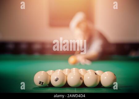 Man is player preparing and aiming to smash white balls in Russian billiards on green table. Stock Photo