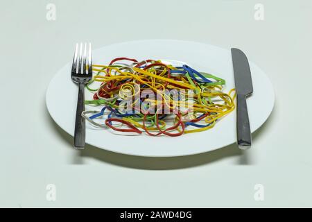 Elastic multi-colored rubber bands lie in a plate like spaghetti Stock Photo