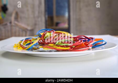 Elastic multi-colored rubber bands lie in a plate like spaghetti Stock Photo