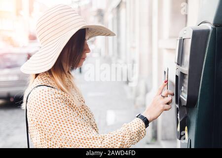 Woman tourist pays for parking space of car through contactless payment phone, Europe. Stock Photo