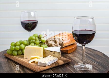 Wine and cheese platter served with grapes on wood surface with white background Stock Photo