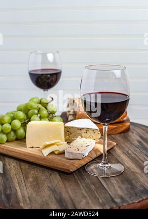 Wine and cheese platter served with grapes on wood surface with white background Stock Photo