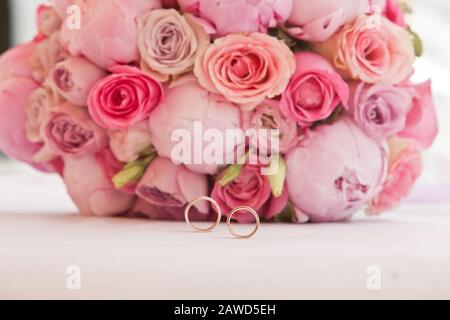 beautiful bouquet of peonies and other pink flowers with wedding rings for newlyweds Stock Photo