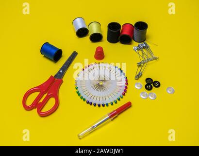 Spools of thread and basic sewing tools including pins, needle, a thimble, and tape measure. Copy space. Long banner format back Stock Photo