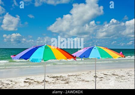 Two Multi-Colored Beach Umbrellas against the Ocean and Sky Stock Photo