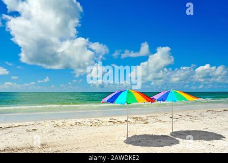 Two Rainbow Colored Beach Umbrellas on the Beach Stock Photo