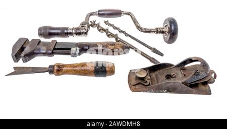 Vintage tools including a hand drill, planer, chisel and wrench on an isolated background Stock Photo