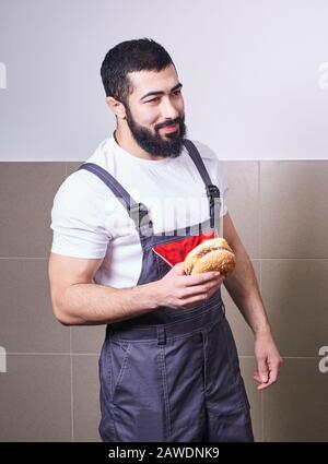 Worker wearing uniform eating burger during a lunch break Stock Photo