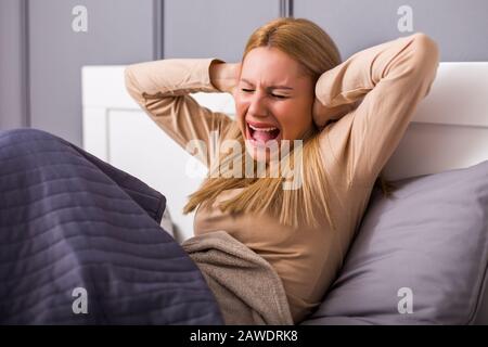 Angry woman disturbed with a noise having problems with sleeping. Stock Photo