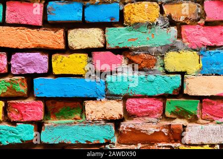 crumbling brick wall in different colors painted. Close up. Stock Photo