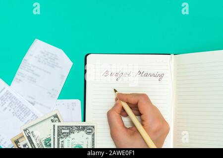 Top view of receipts and cash and woman hand writing in a notepad words Budget Planning. Personal budgeting concept Stock Photo