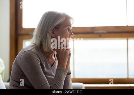 Upset mature woman look in distance feeling sad mourning Stock Photo