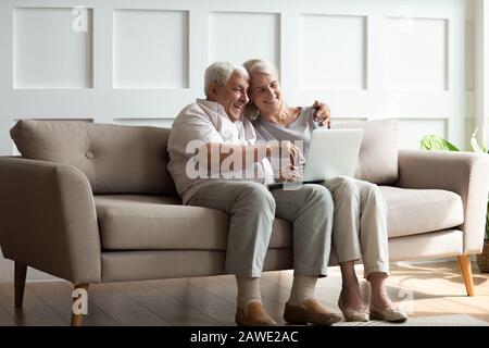 Modern mature couple have fun using laptop at home Stock Photo