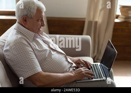 Senior man relax on couch using laptop Stock Photo