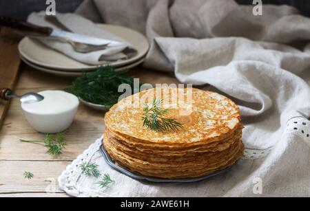 Buckwheat pancakes served with sour cream and dill on a wooden table. Rustic style. Stock Photo