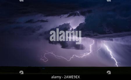 Stormy weather and lightning strike as a thunderstorm clouds sweep across the plains near Broadus, Montana, USA Stock Photo