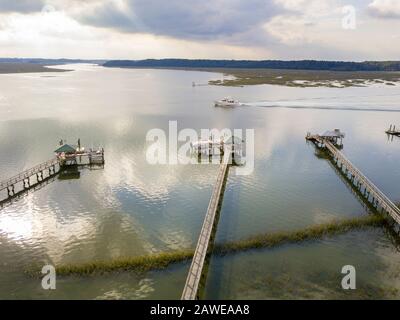 Aerial shot of yacht passing by docks and boathouse on a river in South Carolina. Stock Photo