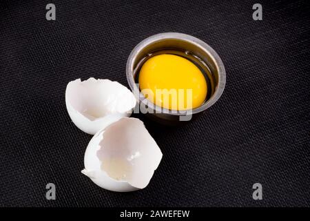 Egg on black with cracked shells and yolk Stock Photo
