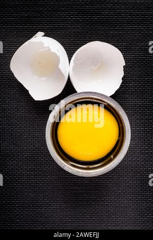 Egg on black with cracked shells and yolk Stock Photo