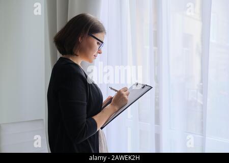Mature woman doctor social worker psychologist taking notes Stock Photo