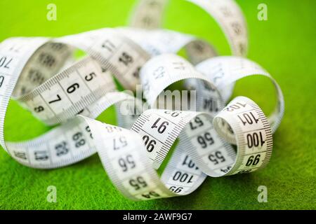 White measuring tape on a green background. Stock Photo