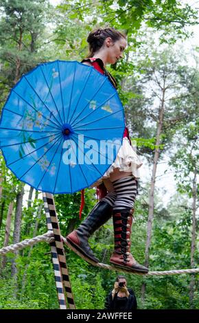 Holly Michigan, USA July 27 2014; a woman in costume with a blue parasol, walks on a rope high above the ground at a Renascence fair Stock Photo