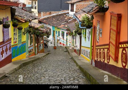 Colorful tile-roofed buildings decorated with zocalos (friezes) line Calle del Recuerdos, a cobblestone pedestrian street in Guatape, Colombia Stock Photo