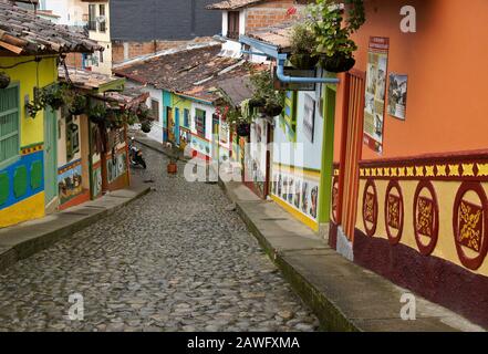 Colorful tile-roofed buildings decorated with zocalos (friezes) line Calle del Recuerdos, a cobblestone pedestrian street in Guatape, Colombia Stock Photo