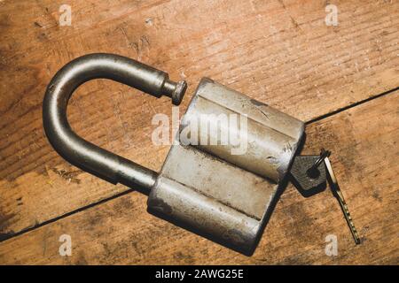 Old rusty lock with a key on a wooden table. Vintage padlock and key on wood background Stock Photo