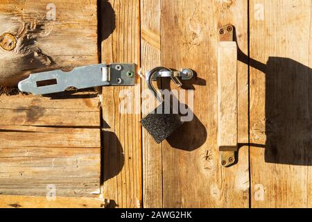 Metal padlock on a wooden door with opened latch Stock Photo
